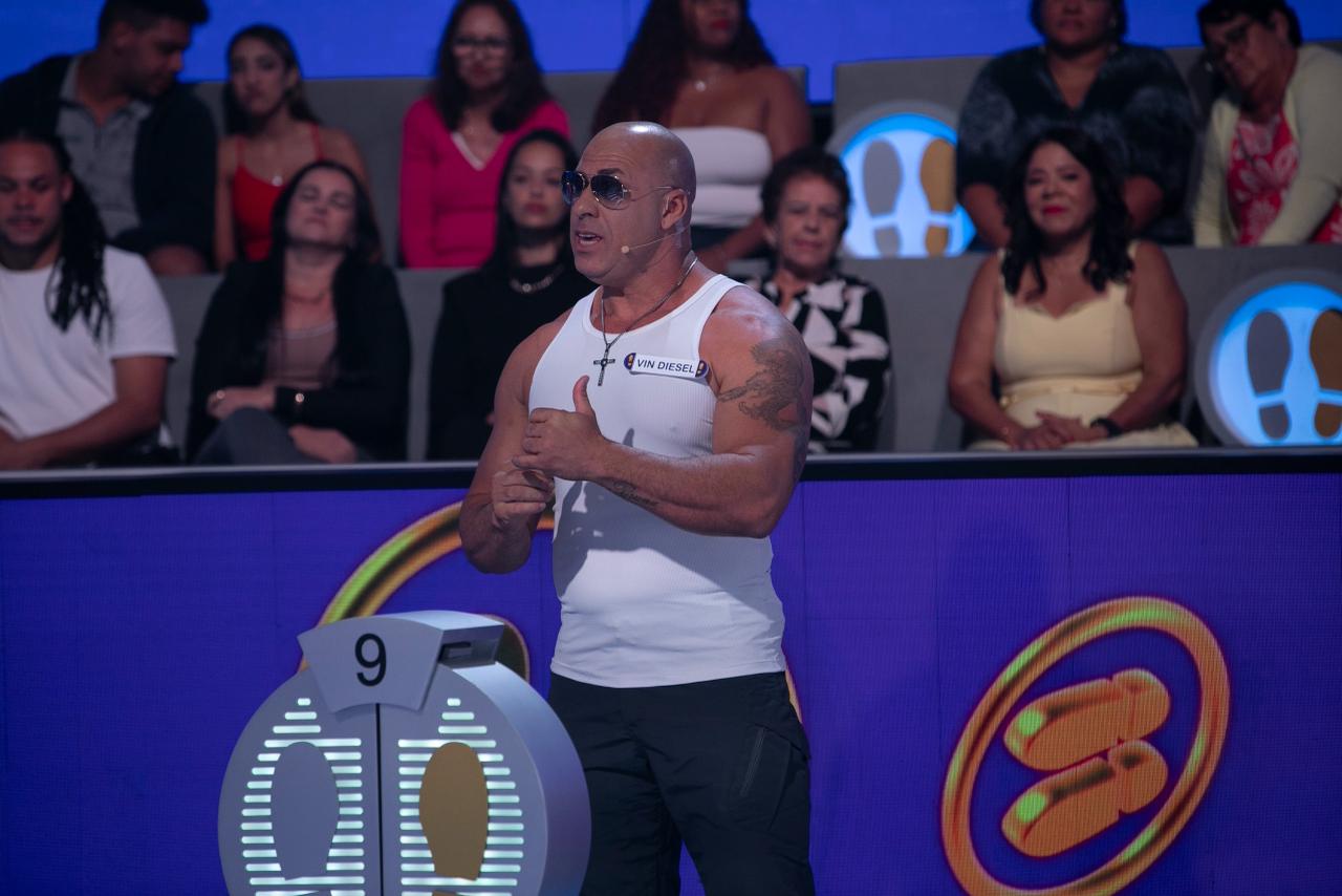 Vin Diesel Brasileiro com crachá VIN DIESEL no palco do SBT diante da plateia